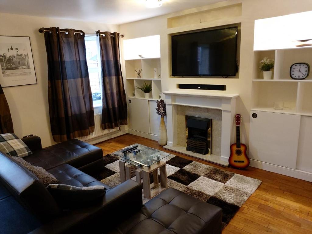 un soggiorno con divano e camino con TV di Heronsgate GH007 a Woolwich