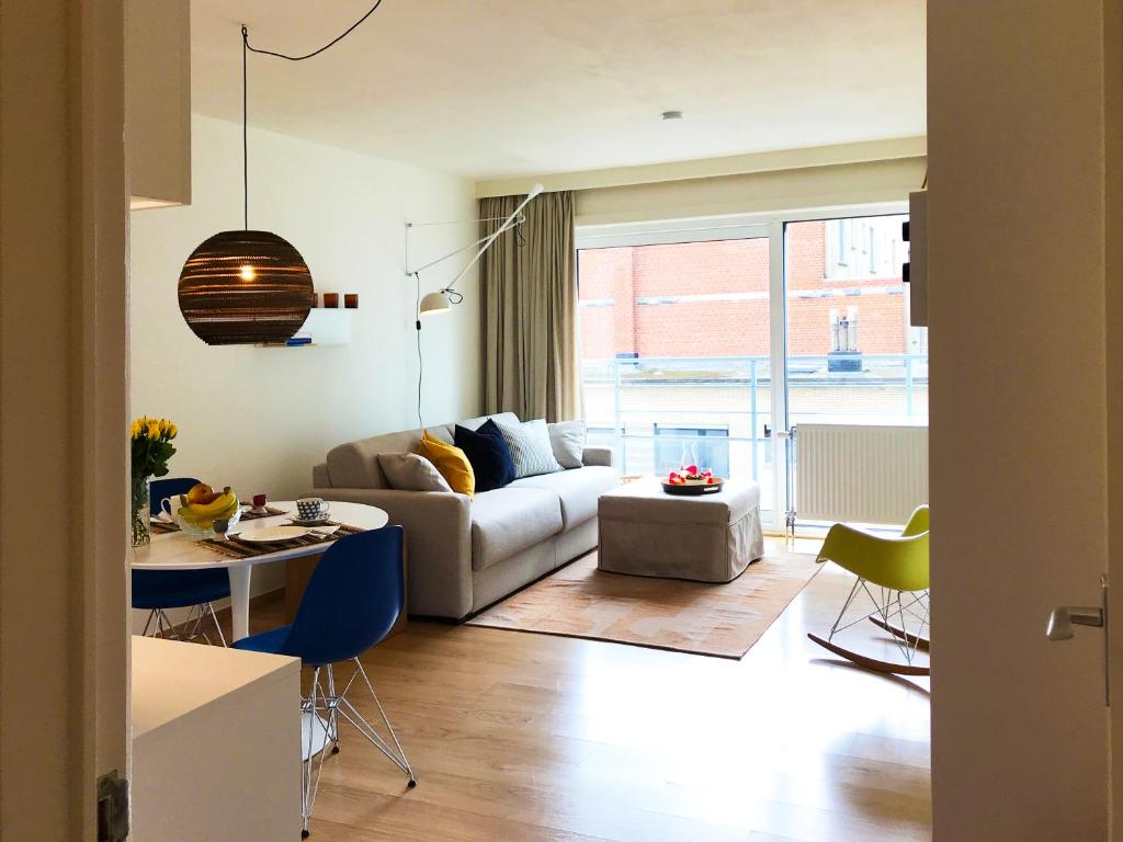 een woonkamer met een bank en een tafel en stoelen bij Studio zee in Nieuwpoort