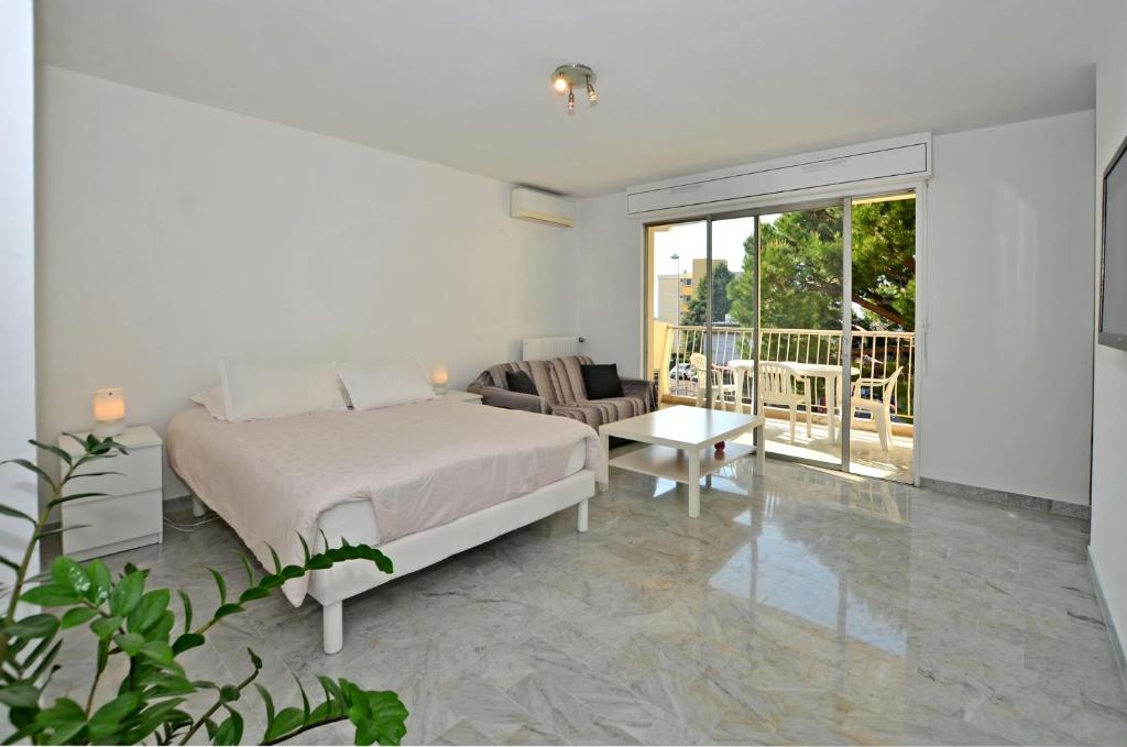 a white bedroom with a bed and a couch at Azur 3000 in Saint-Laurent-du-Var