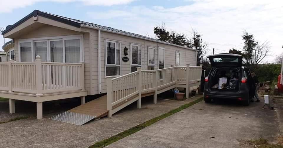 ein winziges Haus mit einem Auto daneben geparkt in der Unterkunft PRIVATELY OWNED Stunning Caravan Seawick Holiday Park St Osyth in Jaywick Sands
