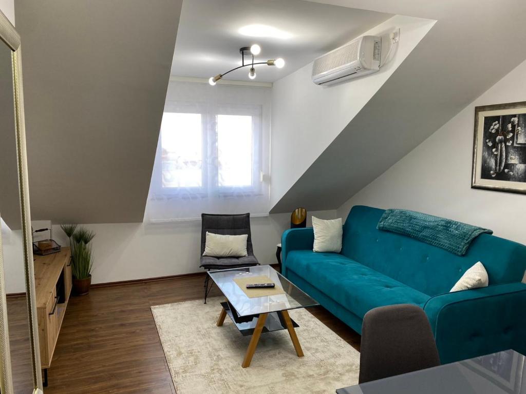 a living room with a blue couch and a table at APARTMAN PAVIĆ in Vinkovci