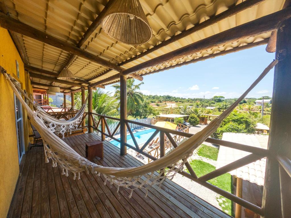 a hammock on a porch with a view of a pool at Apto com lazer em rancho na Praia de Imbassaí - BA in Mata de Sao Joao