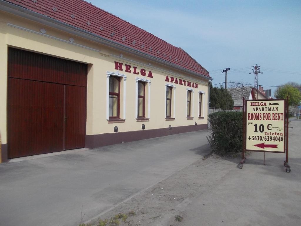 a building with a sign in front of a garage at Helga Apartman in Makó