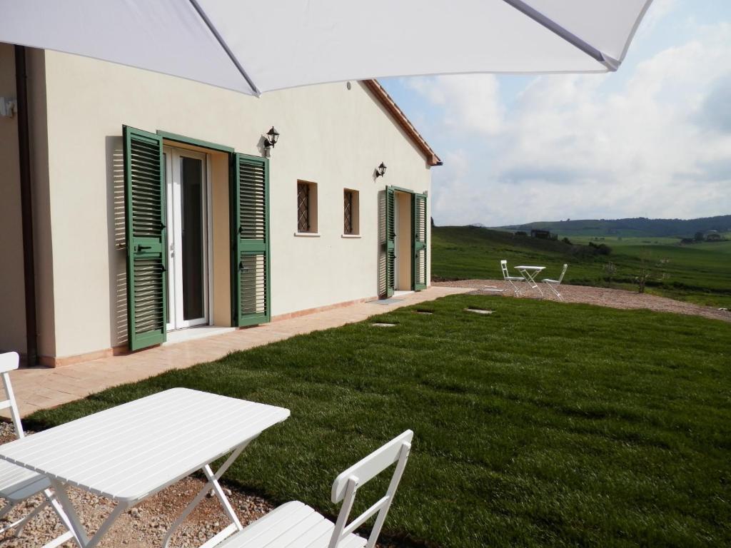 a white house with green shutters and a lawn at Poggiobono Country House in Marsiliana