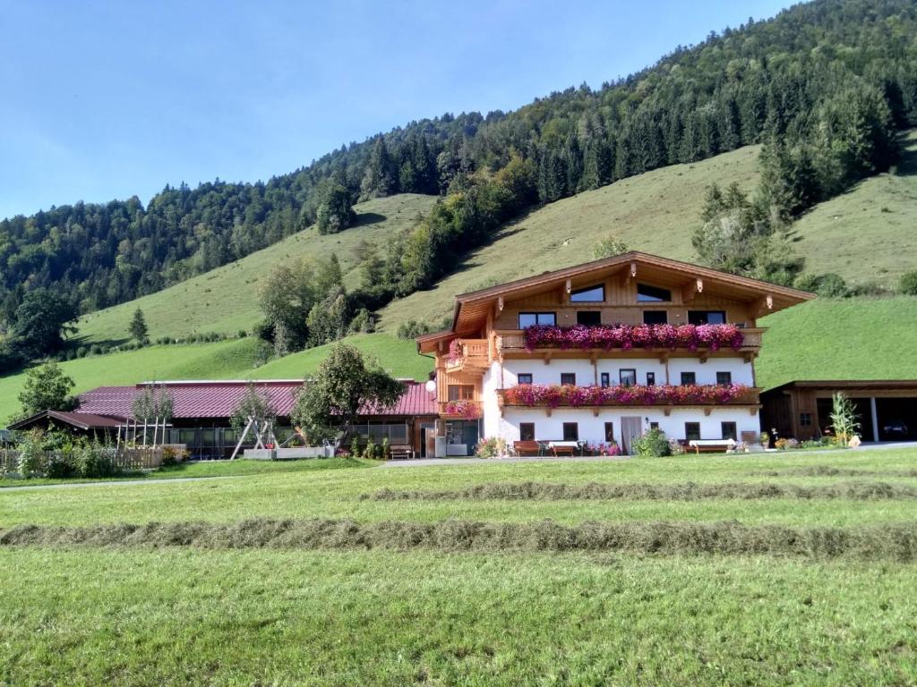a house with flowers on the side of a field at BIO- Bauernhof Obermaurach in Walchsee