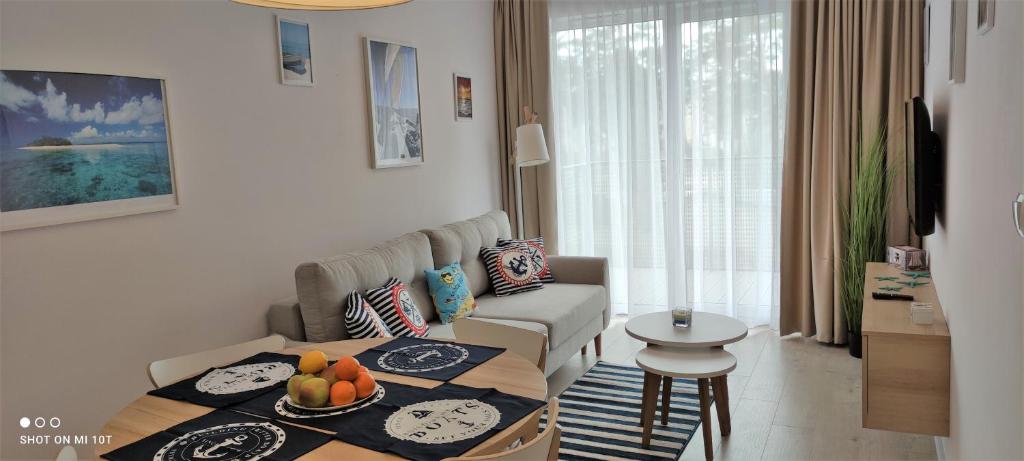 ein Wohnzimmer mit einem Sofa und einem Tisch in der Unterkunft Apartament Morski - Olimpijska 2, Mielno in Mielno