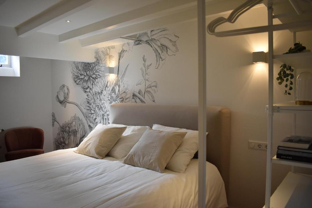 a bedroom with a bed with white sheets and tropical wallpaper at Stadsdromer in Middelburg
