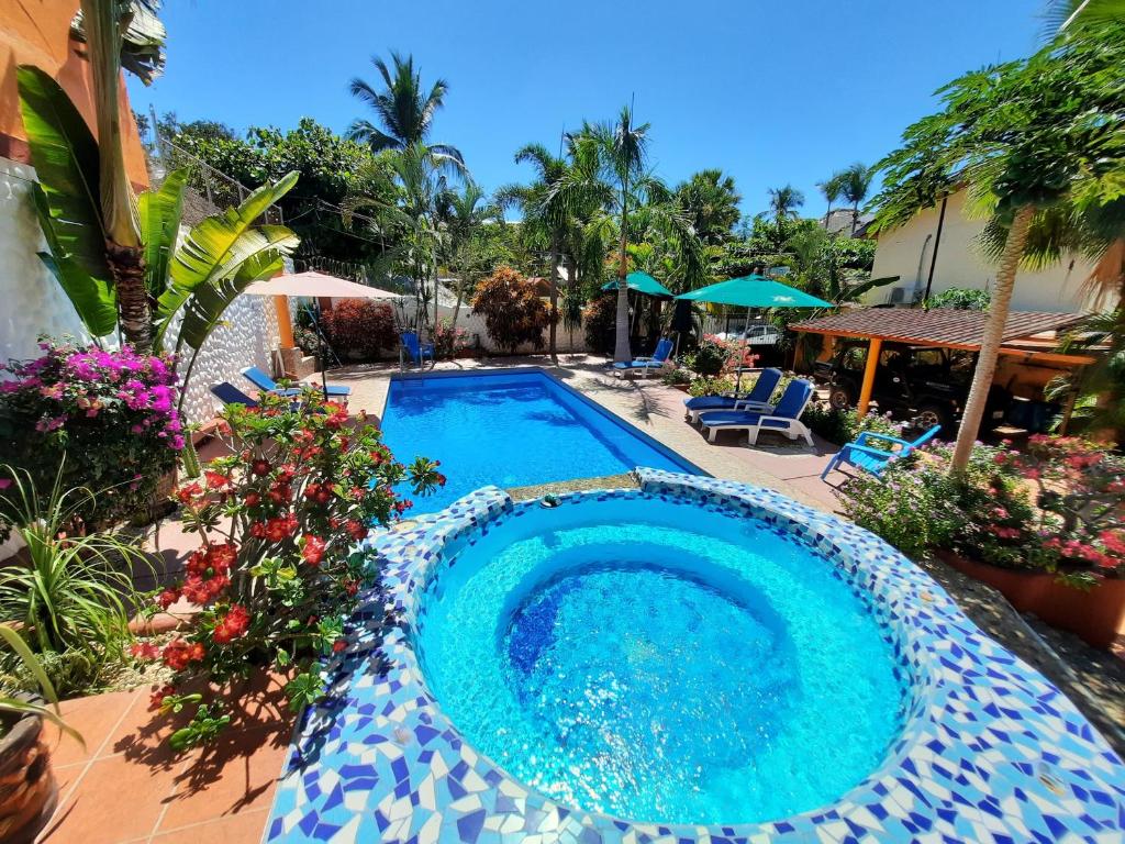 a swimming pool in a yard with flowers and plants at Hotelito Swiss Oasis -Solo Adultos - Adults only in Puerto Escondido