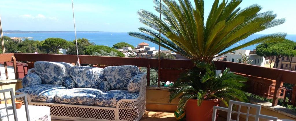 um sofá sentado numa varanda com uma palmeira em Attico Panoramico Vista Mare em Anzio