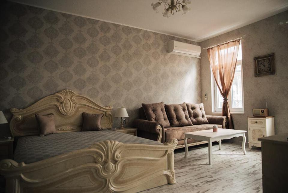 a bedroom with a bed and a couch and a table at Апартамент Барок in Lovech