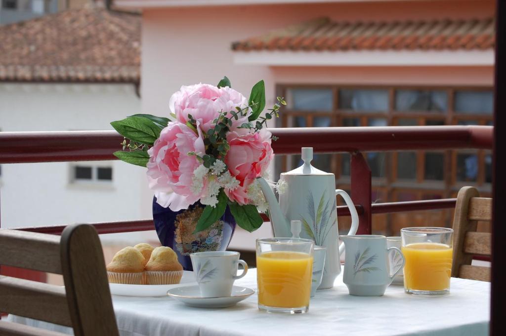 einen Tisch mit einer Vase rosa Blumen und Orangensaft in der Unterkunft Gestiona2R - Apartamento 3 Habitaciones Landaburu in Posada de Llanes