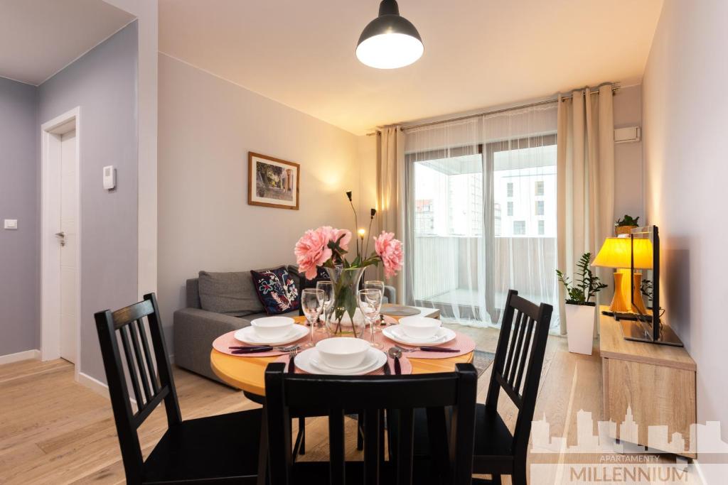 a dining room and living room with a table and chairs at JM Millennium Port in Warsaw