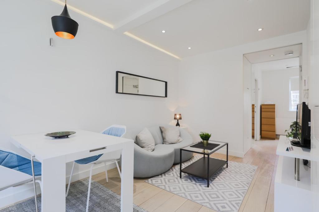 a white living room with a couch and a table at StayInn Soho Apartments in London