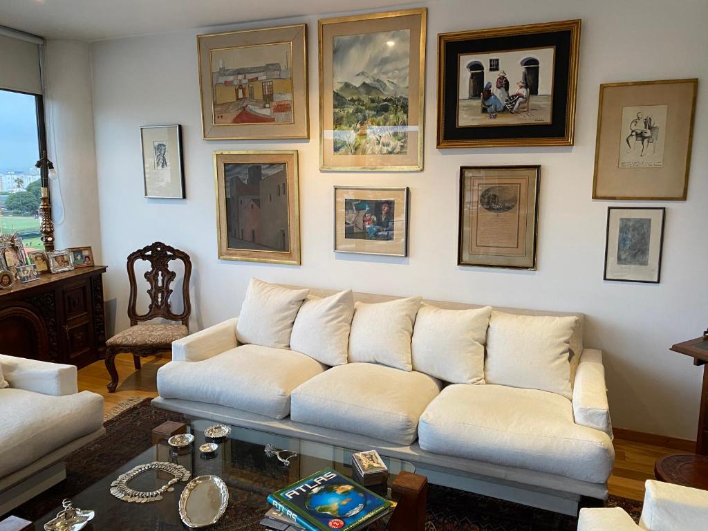 uma sala de estar com um sofá branco e quadros na parede em DEPARTAMENTO PREMIUM - 2 HAB. Y 2 BAÑOS em Salta