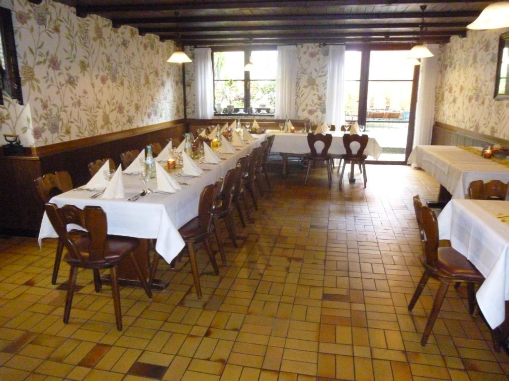 uma sala de jantar com mesas e cadeiras brancas e janelas em Hotel Ehinger Rose em Ehingen