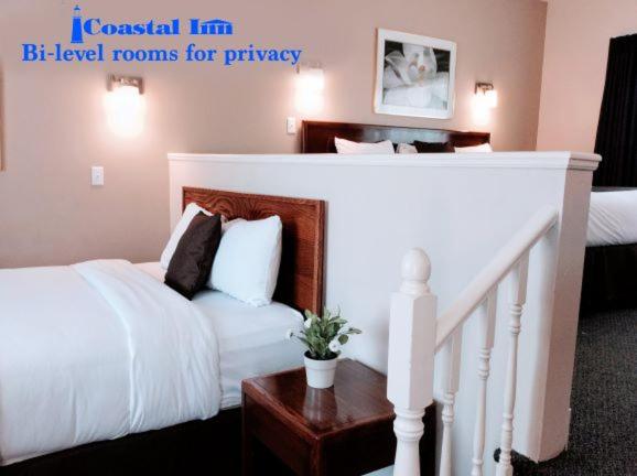 a bedroom with a white bed and a stairway at Coastal Inn Antigonish in Antigonish