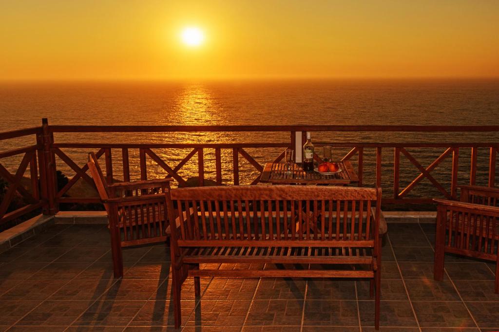 una mesa y sillas en un balcón con vistas a la puesta de sol en Irida, en Armenistis