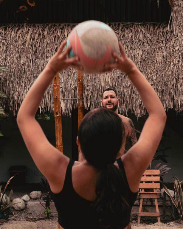 a woman holding a ball in front of a man at El Zoo Hostel, Bar & Pool in Palomino