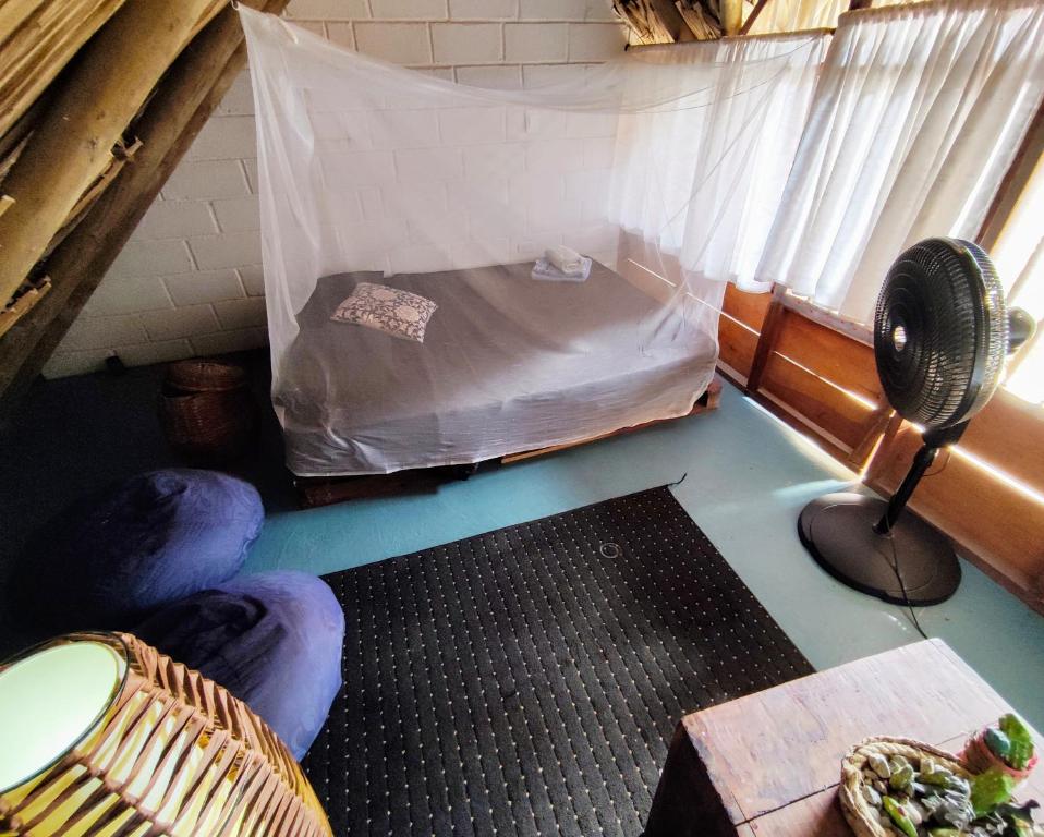 a small room with a bed and a fan at El Zoo Hostel, Bar & Pool in Palomino