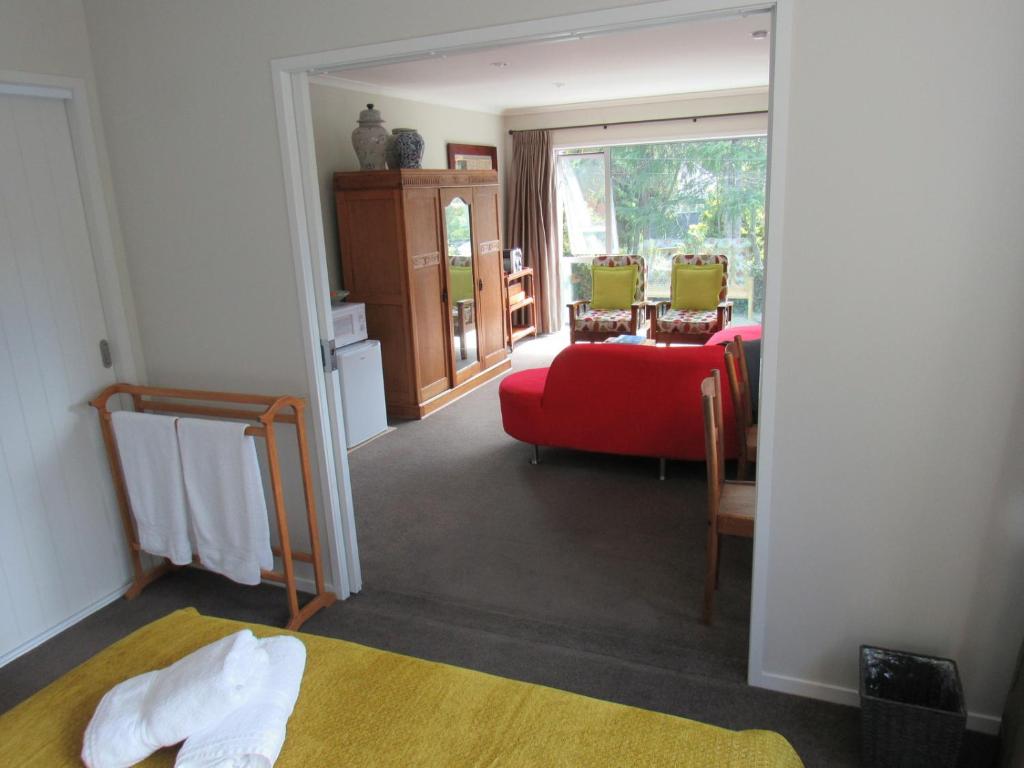 Habitación con sofá rojo y silla roja en Castor Bay Homestay, en Auckland