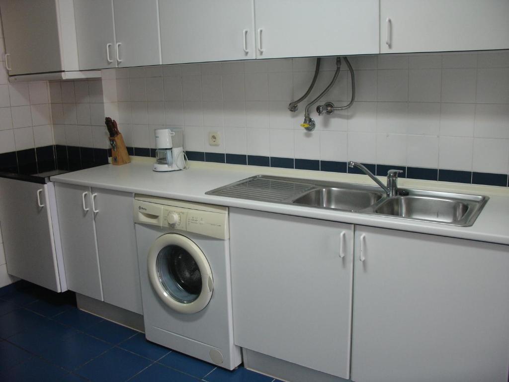 a kitchen with a sink and a washing machine at Apartamento Capela in Funchal