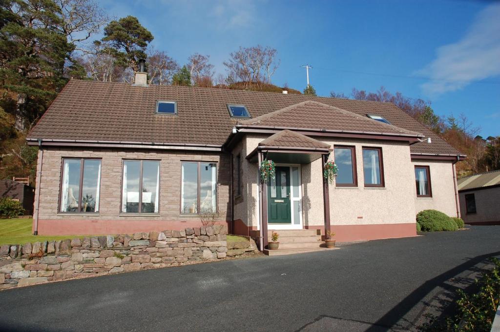 una casa de ladrillo con una pared de piedra en Heatherdale B & B, en Gairloch