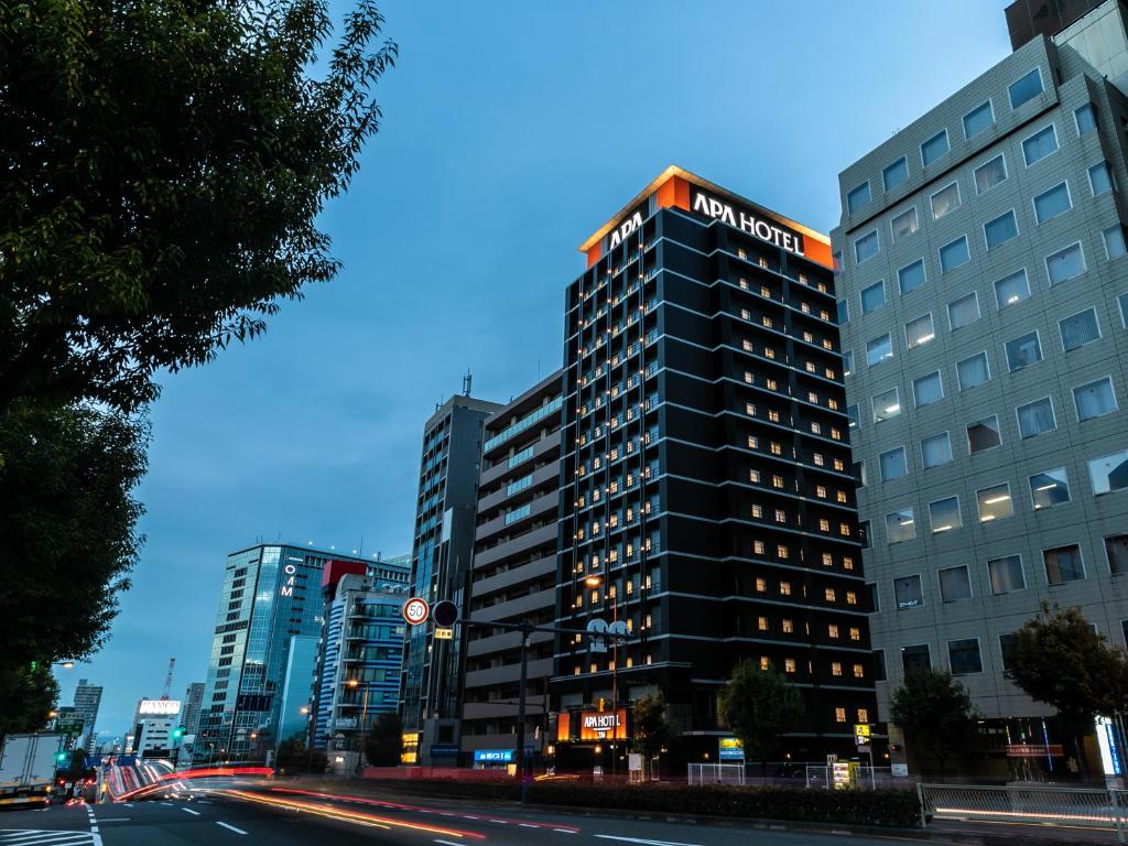 ein hohes schwarzes Gebäude in einer Stadtstraße in der Unterkunft APA Hotel Osaka Temmabashi-Ekimae in Osaka