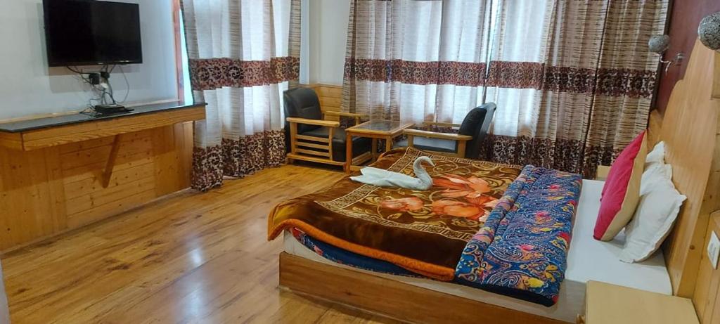 a bedroom with a bed and a tv in a room at New Apple Cottage in Manāli