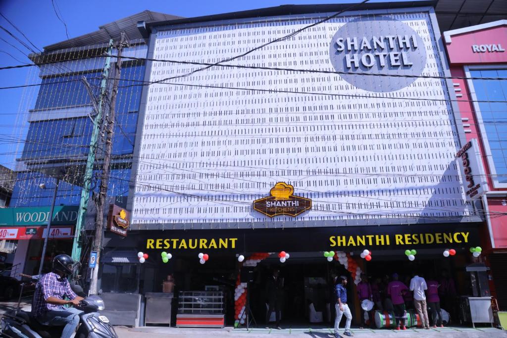 a man riding a motorcycle in front of a hotel at Shanthi Residency in Pathanāmthitta