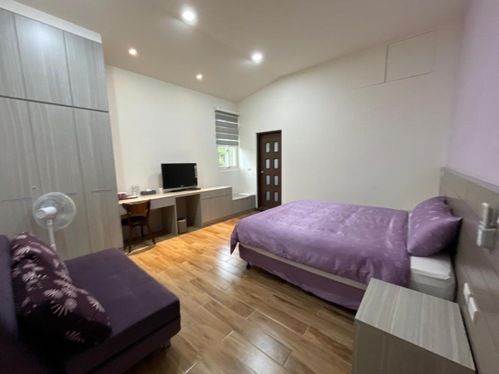 una camera con letto viola e scrivania di 耘禾莊園民宿 台東縣民宿編號1273號 a Guanshan