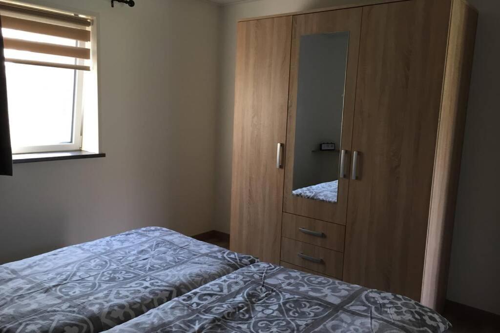 a bedroom with a bed and a wooden cabinet at Bungalow op bedrijf met melkkoeien in De Cocksdorp