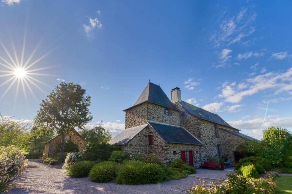 an old stone building with the sun in the sky at Manoir le Courtillon in Le Pont Réan