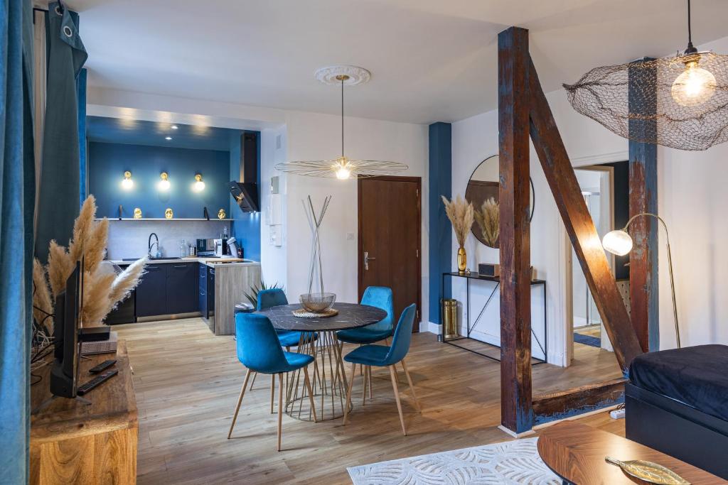 uma sala de estar e cozinha com uma mesa e cadeiras azuis em PARENTHESE - Le Vignemale em Lourdes