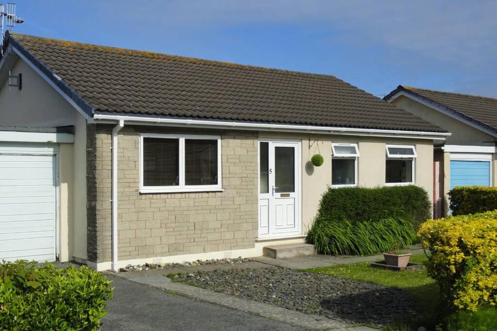 a house with a white door in a yard at Beautiful family getaway, close to the beach in Fairbourne
