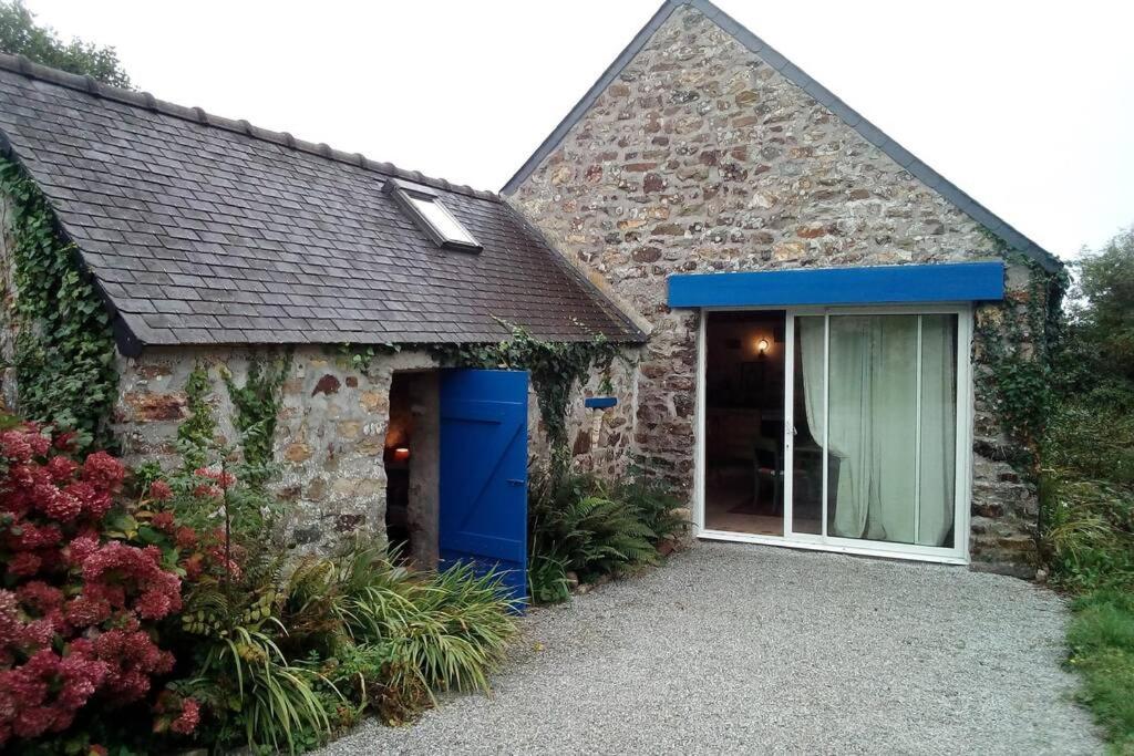 ein Steinhaus mit einer blauen Tür und einem Fenster in der Unterkunft Le cottage in Crozon