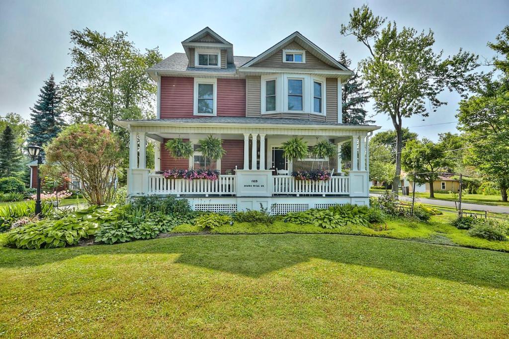 uma casa vermelha com um alpendre branco e um quintal em THE YORK HOUSE em Fort Erie