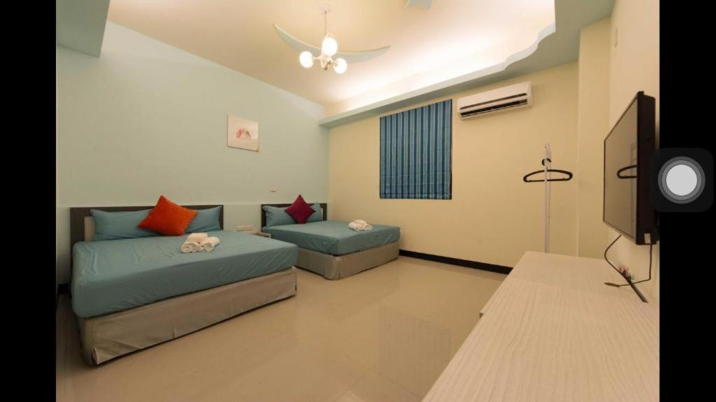 a living room with two beds and a tv at Kenting Orange Homestay in Hengchun
