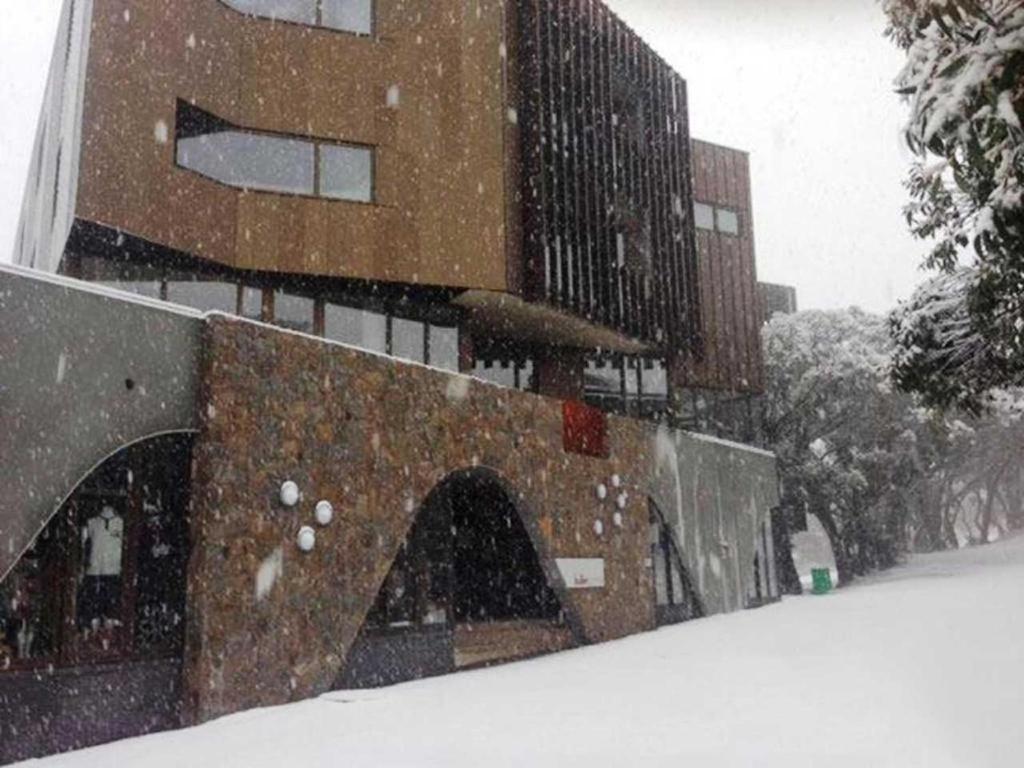 uma tempestade de neve em frente a um edifício em Buller Central Hotel em Mount Buller