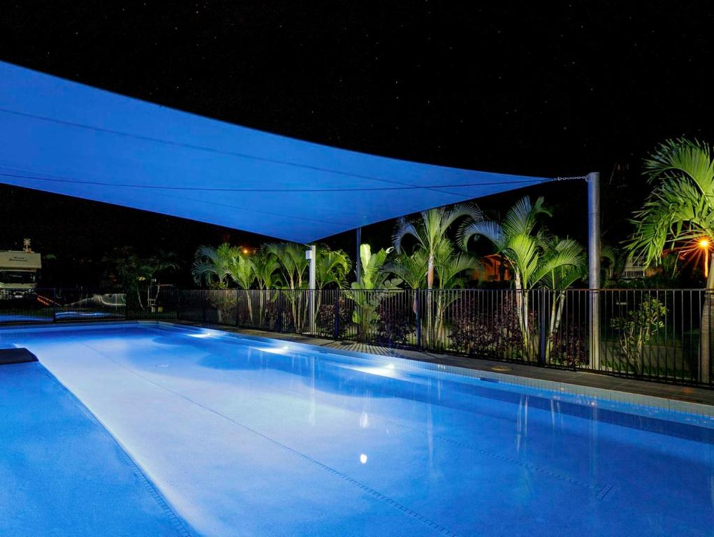 a large swimming pool at night with a blue canopy at Queens Beach Tourist Village in Bowen