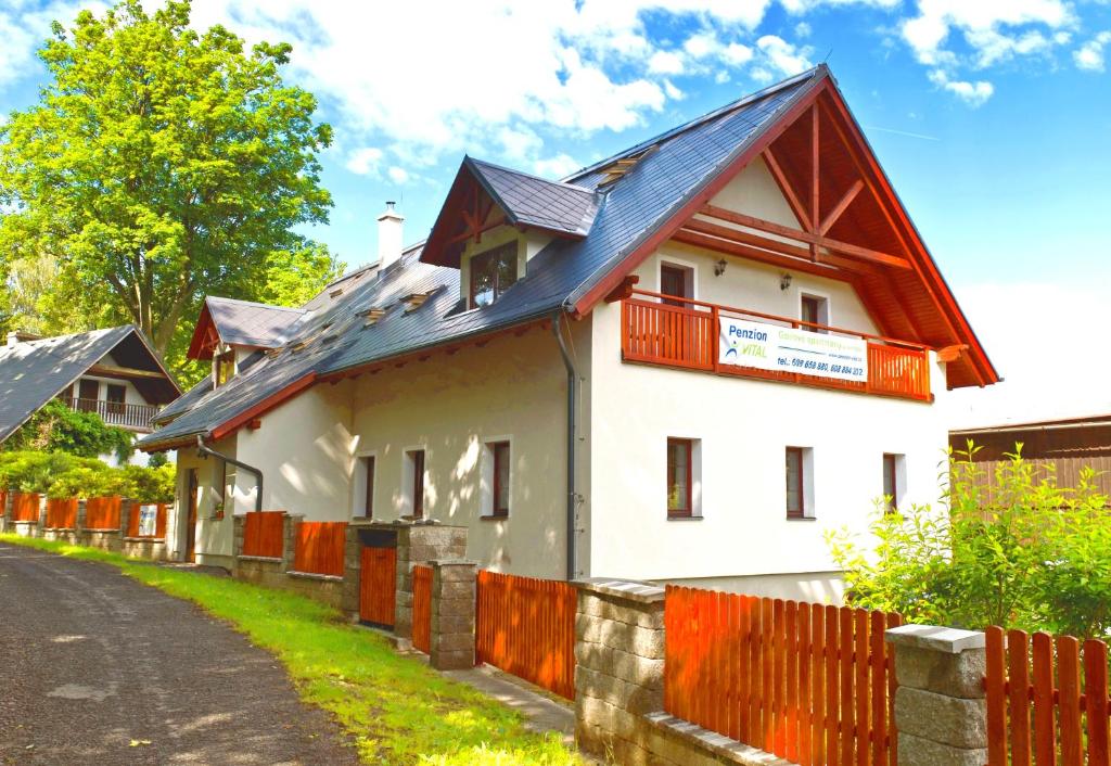 a white house with a red roof and a fence at Penzion Vital in Liberec