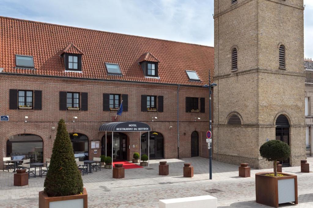 un grand bâtiment en briques avec une tour d'horloge dans l'établissement Hôtel du Beffroi Gravelines Dunkerque, à Gravelines