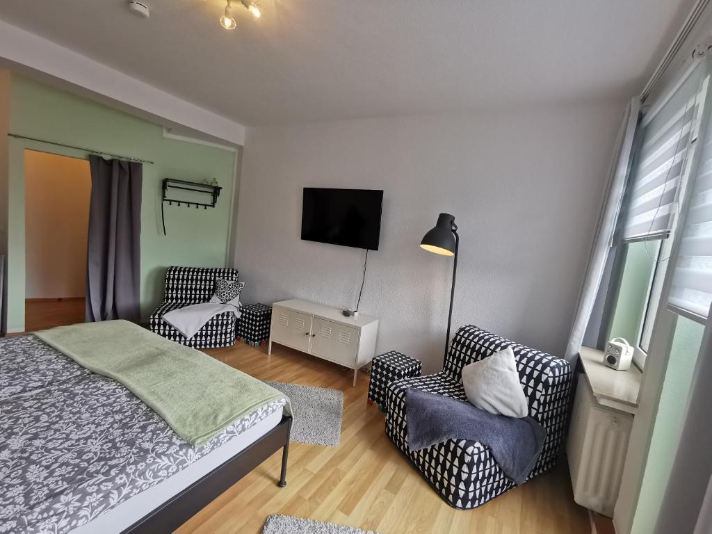 a bedroom with a bed and two chairs and a tv at Die Birke in Bremen