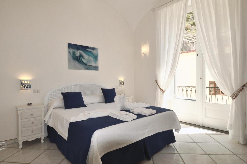 Schlafzimmer mit einem Bett mit blauer und weißer Bettwäsche in der Unterkunft L'Ancora Amalfi Dreams in Minori