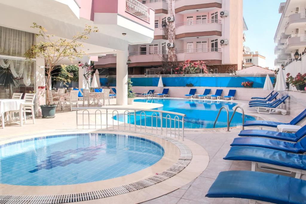 uma grande piscina com cadeiras azuis ao lado de um edifício em Bella Rose Apart Hotel, Renovated in 2023! em Alanya