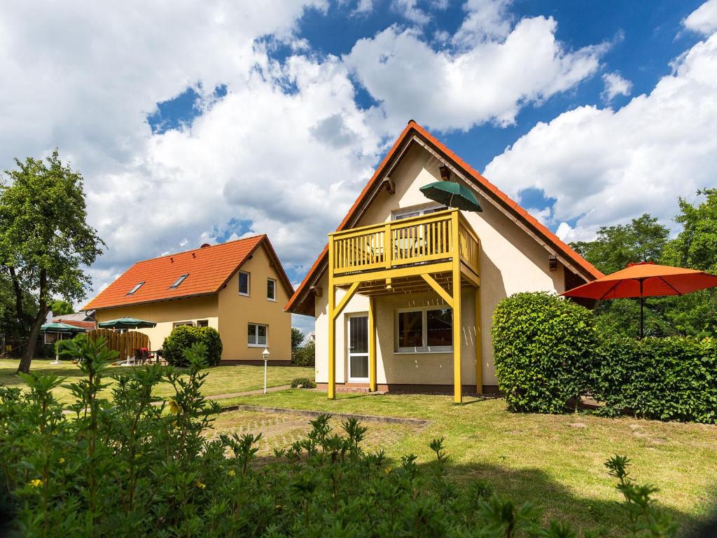 a yellow house with a balcony and an orange roof at Müritz Ferienhaus in Seenähe in Groß Kelle