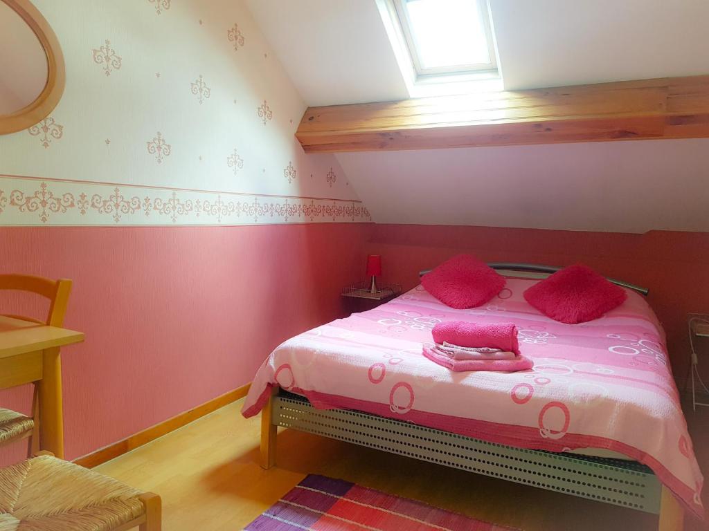 a bedroom with a bed with pink pillows and a window at Chambres d'Hôtes Vadiera in Autun