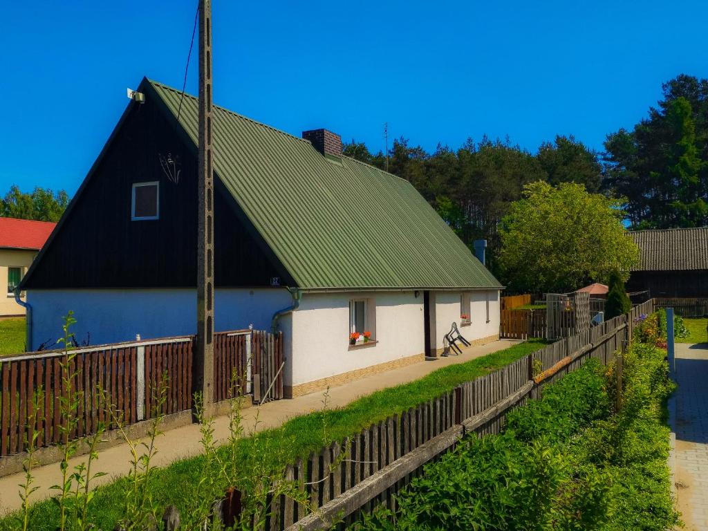 een huis met een groen dak en een hek bij Zielona Chałupa in Tuchorza Nowa