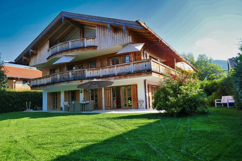 uma casa grande com um grande relvado em frente em Bodenschneid Suiten Ringbergblick em Rottach-Egern