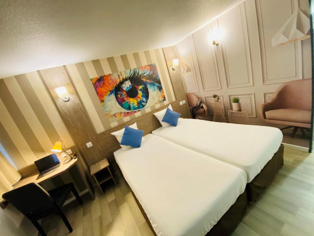 a room with two beds and a table and a chair at Hotel RBX - Roubaix Centre in Roubaix