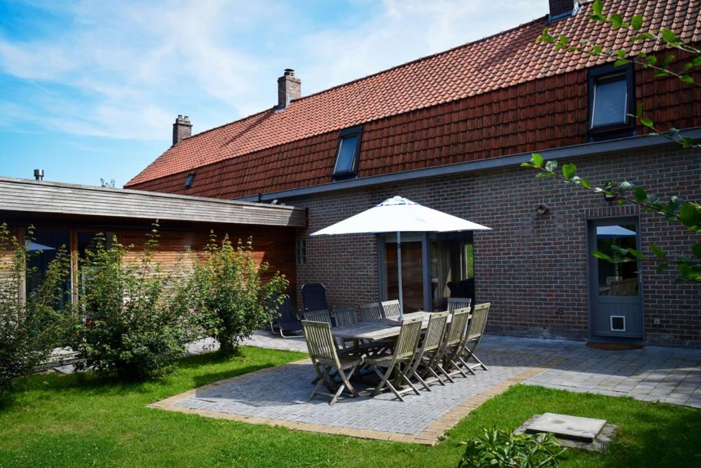 a table and chairs with an umbrella in front of a house at Doeselie deux in Ronse